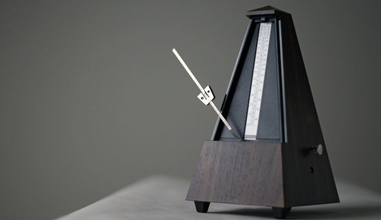 Metronom aus Holz auf Tisch vor grauem Hintergrund