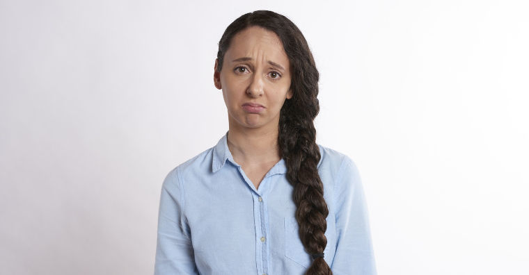 Traurige Frau vor einheitlichem hellen Hintergrund